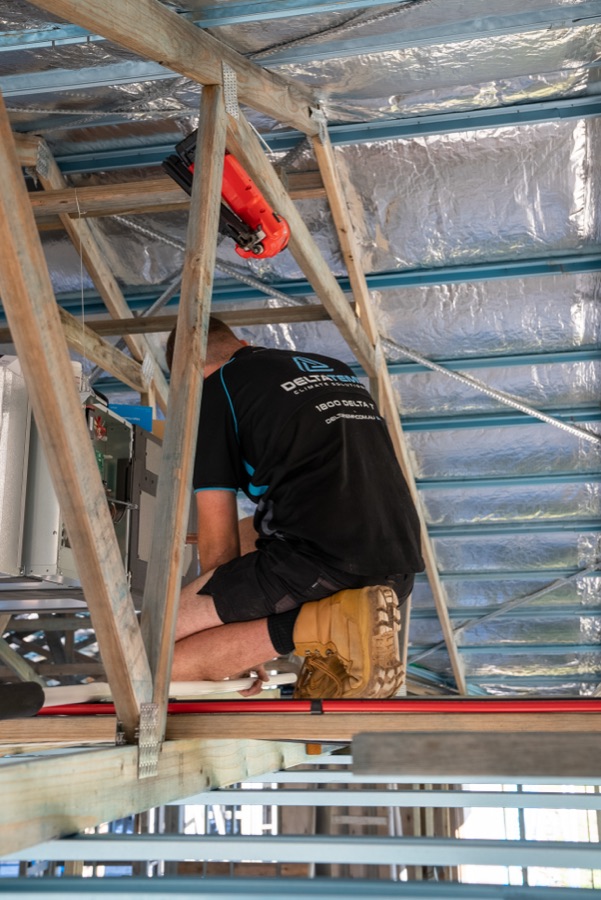 Delta Temp technician working in a roof space during a ducted installation