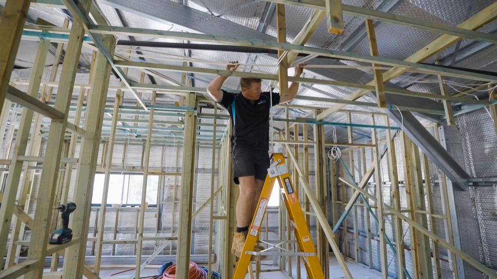 A Delta Temp installer working in the frame of a new home