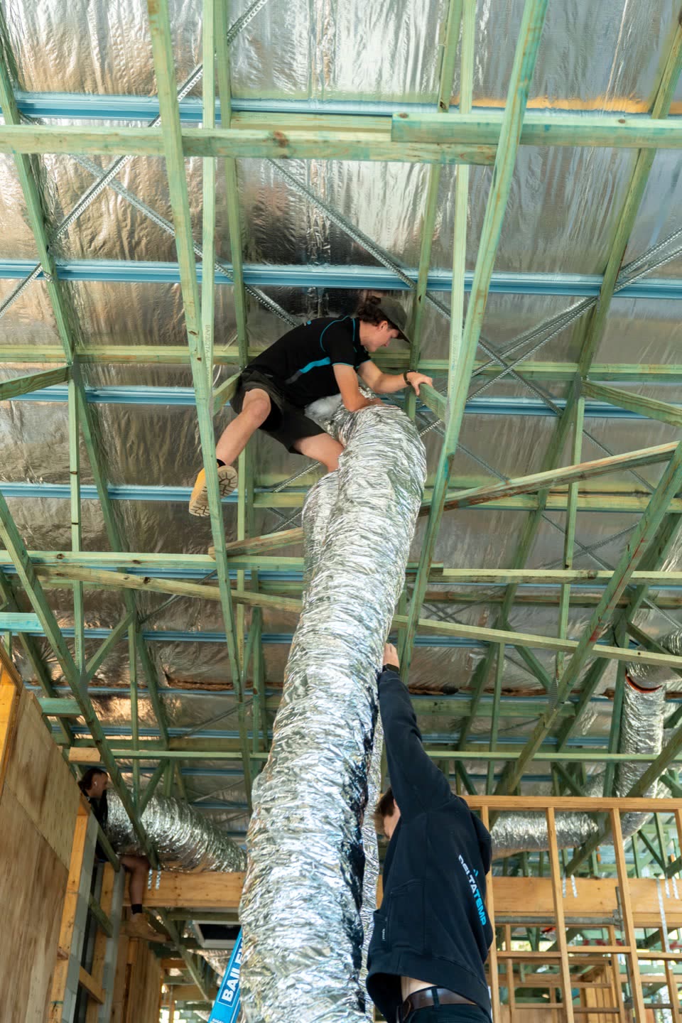 A Delta Temp technician working in a ceiling space