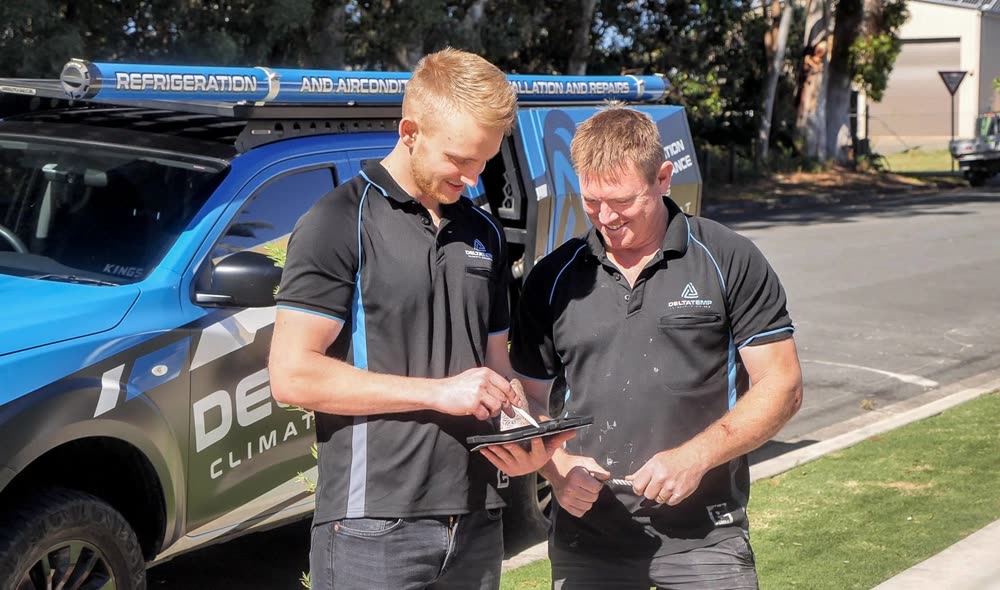 Two Delta Temp team members reviewing a job on a tablet